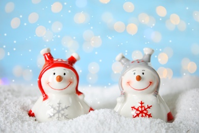 Decorative snowmen on artificial snow against blurred festive lights