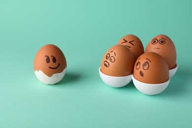 Photo of Eggs with drawn faces on turquoise background. Exhibitionist concept