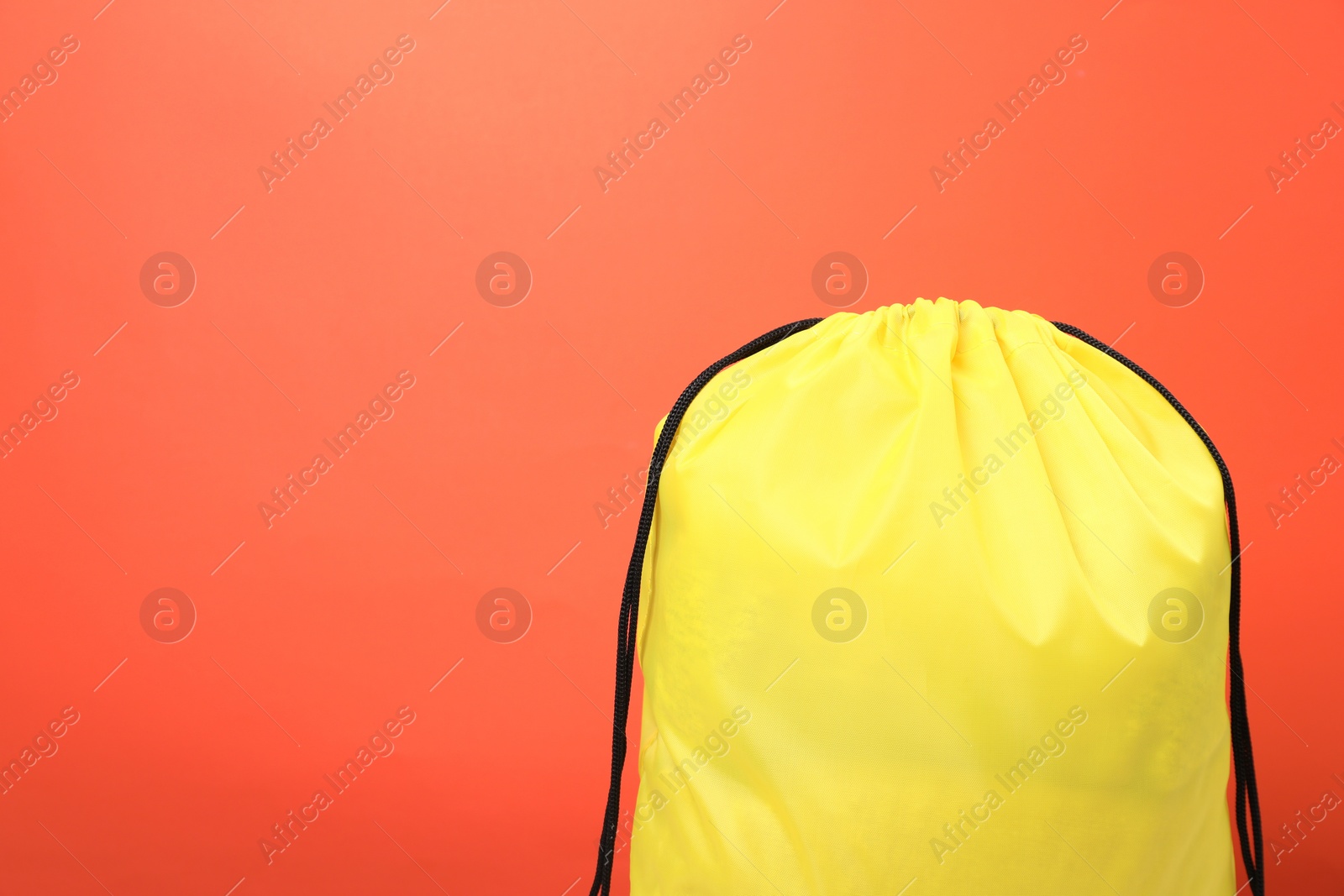 Photo of Yellow drawstring bag on orange background. Space for text
