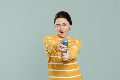 Photo of Young woman blowing up party popper on light grey background