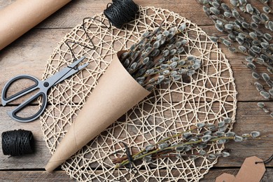 Photo of Beautiful bouquet of pussy willow branches and wrapping materials on wooden table, flat lay