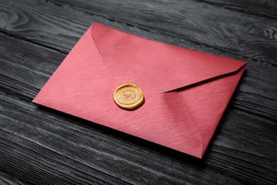 Photo of Envelope with wax seal on black wooden background
