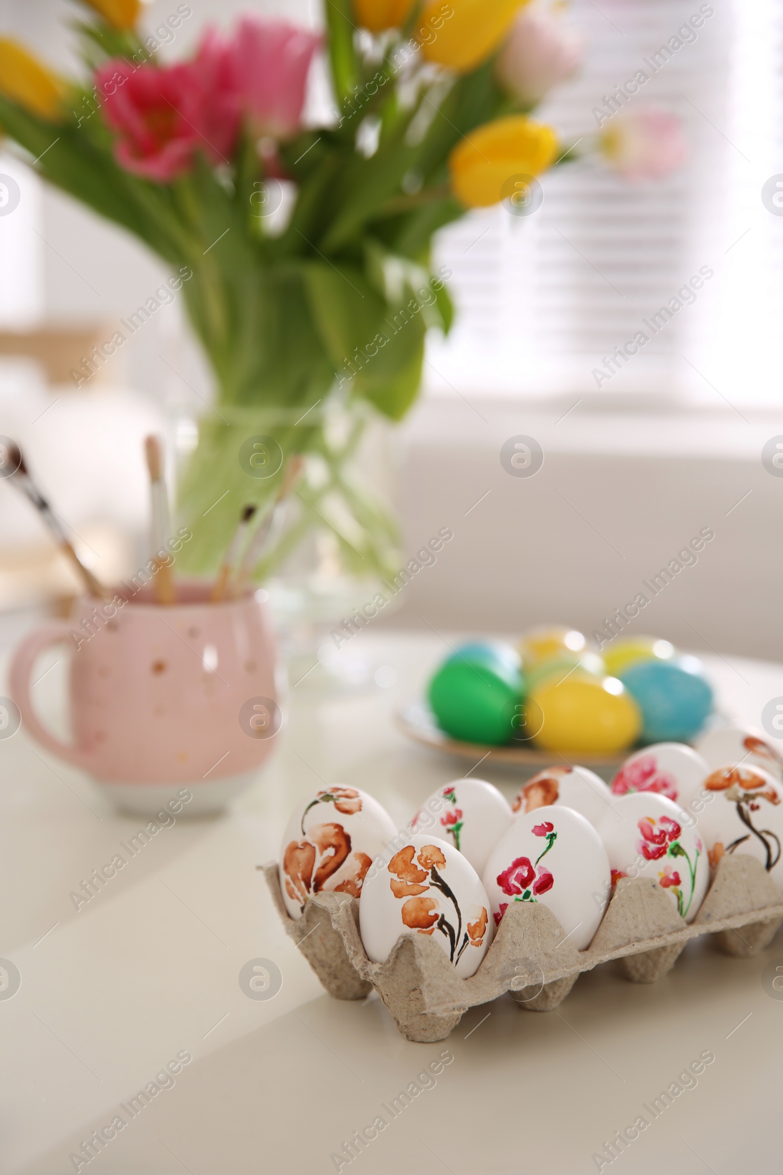 Photo of Beautifully painted Easter eggs on white table indoors, space for text