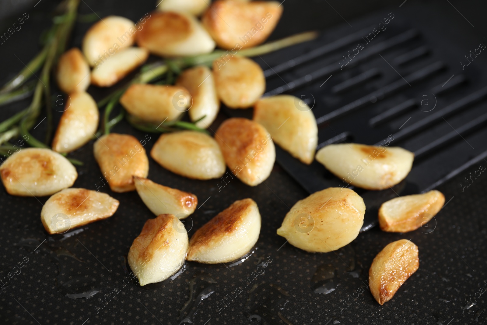 Photo of Frying pan with fried garlic cloves, closeup