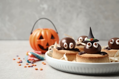 Photo of Delicious biscuits with chocolate spiders on light grey table. Halloween celebration