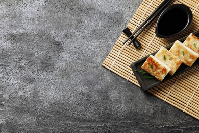 Photo of Delicious turnip cake with green onion, soy sauce and chopsticks on grey table, top view. Space for text