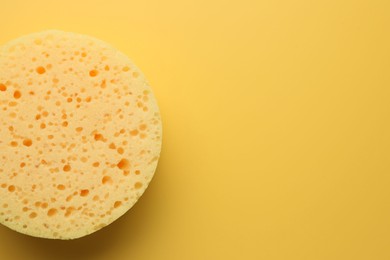 Sponge on yellow background, top view. Space for text