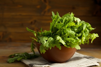 Photo of Fresh arugula in bowl on wooden table