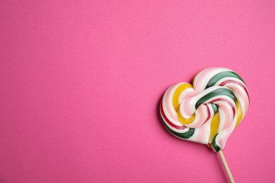 Photo of Stick with heart shaped lollipop on pink background, top view. Space for text