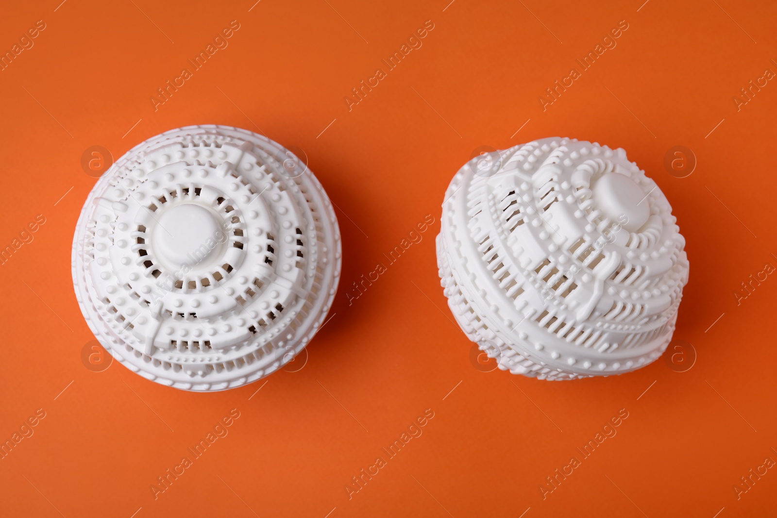 Photo of Dryer balls for washing machine on orange background, flat lay