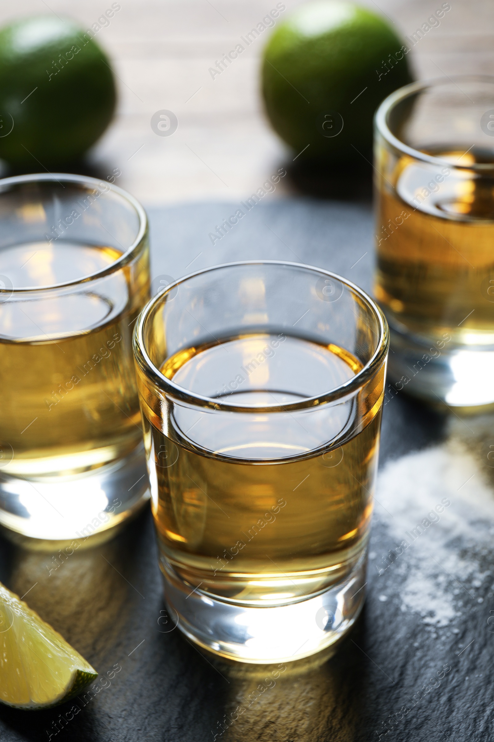 Photo of Mexican Tequila shots, lime slices and salt on wooden table