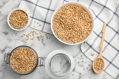 Photo of Uncooked green buckwheat grains on white marble table, flat lay