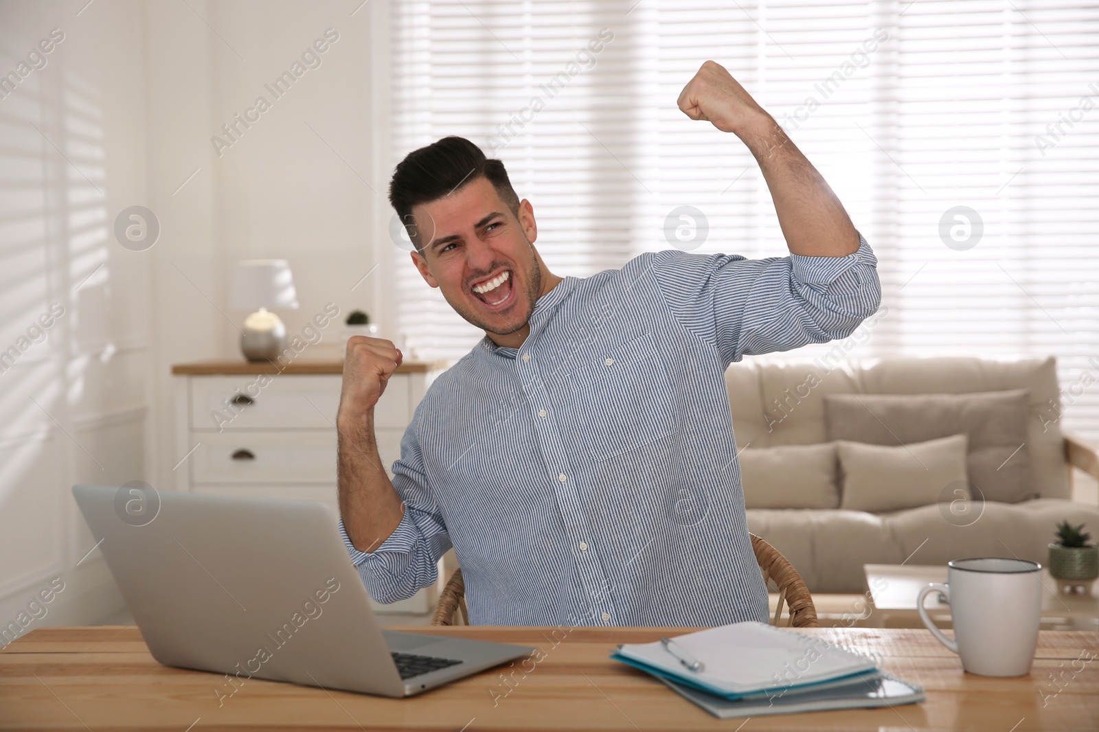 Photo of Emotional man participating in online auction using laptop at home