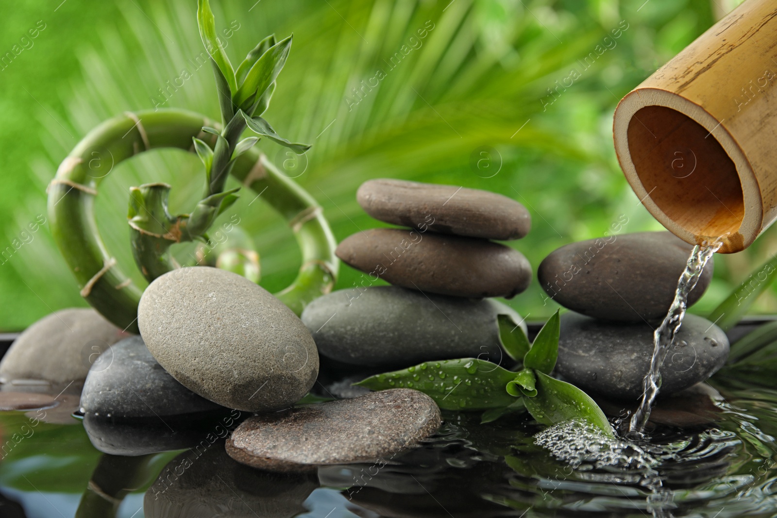 Photo of Composition with stones and bamboo fountain against blurred background. Zen concept