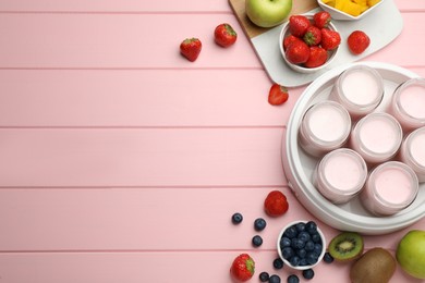 Photo of Modern yogurt maker with full jars and different fruits on pink wooden table, flat lay. Space for text