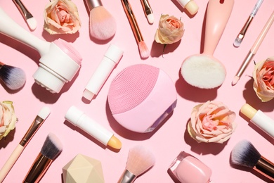 Different makeup brushes, accessories and flowers on pink background, flat lay