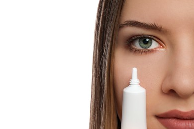 Photo of Young woman holding tube of eye cream on white background, closeup