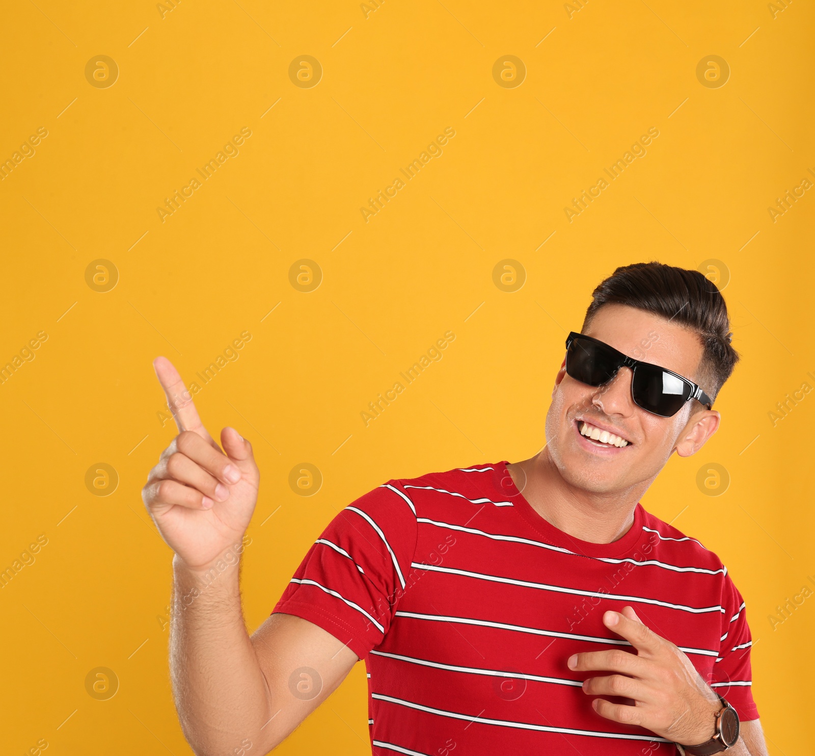 Photo of Handsome man wearing sunglasses on yellow background