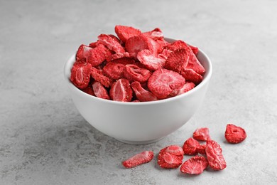Photo of Bowl and dried strawberries on light grey table