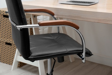 Photo of Stylish workplace interior with office chair and wooden table, closeup