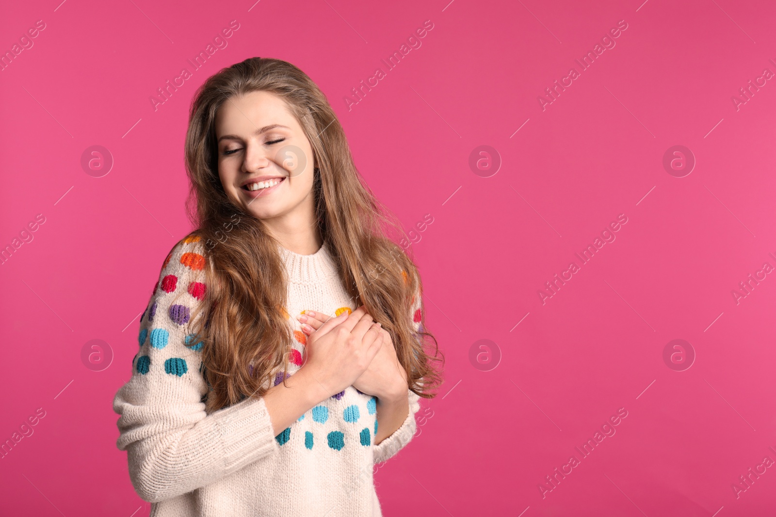 Photo of Young woman holding hands near heart on color background. Space for text