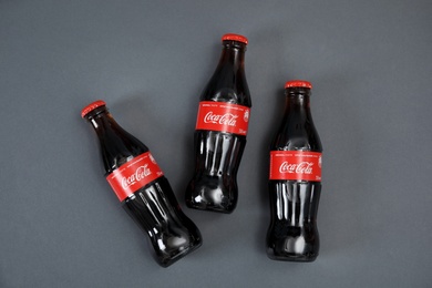 Photo of MYKOLAIV, UKRAINE - NOVEMBER 14, 2018: Bottles of Coca-Cola on grey background, top view