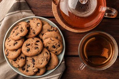 Photo of Delicious chocolate chip cookies and tea on wooden table, flat lay