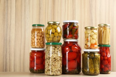 Photo of Jars of pickled vegetables on wooden table