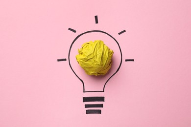 Photo of Idea concept. Light bulb made with crumpled paper and drawing on pink background, top view