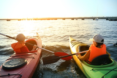 Photo of Little children kayaking on river, back view. Summer camp activity