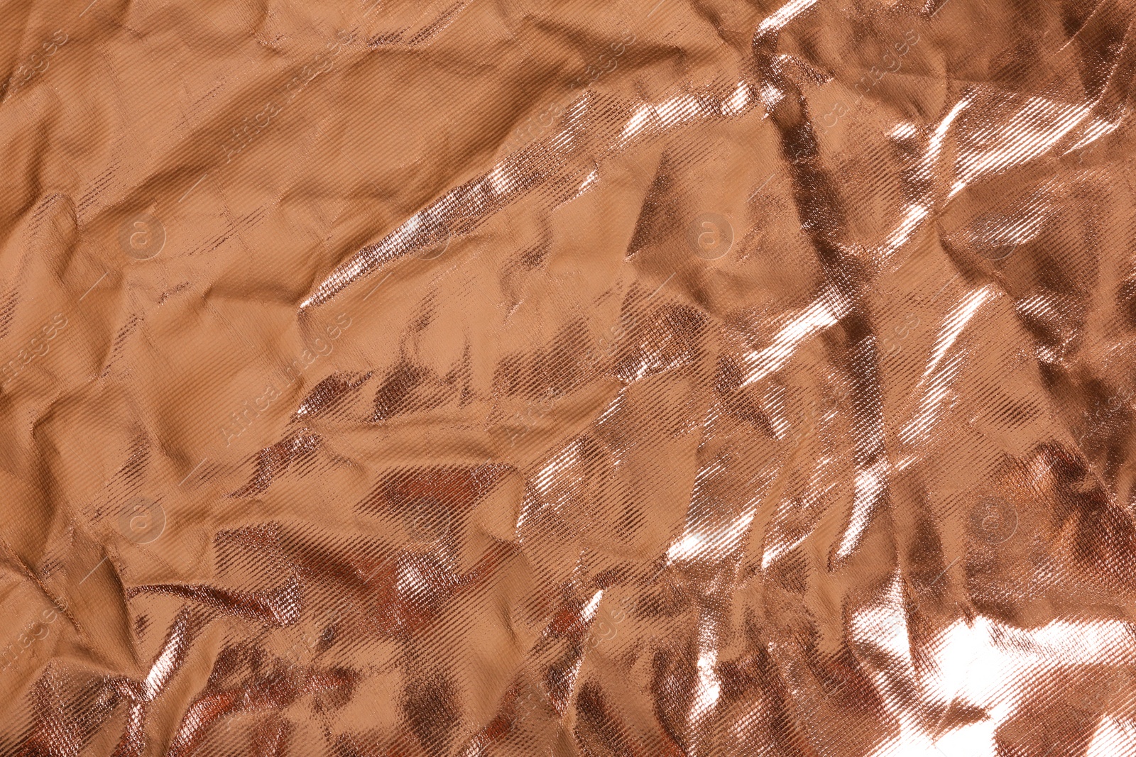 Photo of Crumpled rose gold foil as background, closeup view