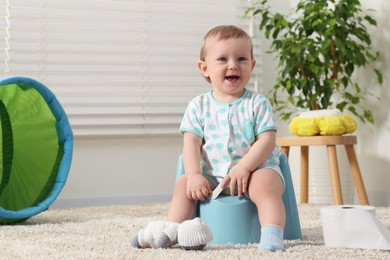 Photo of Little child sitting on plastic baby potty indoors. Space for text