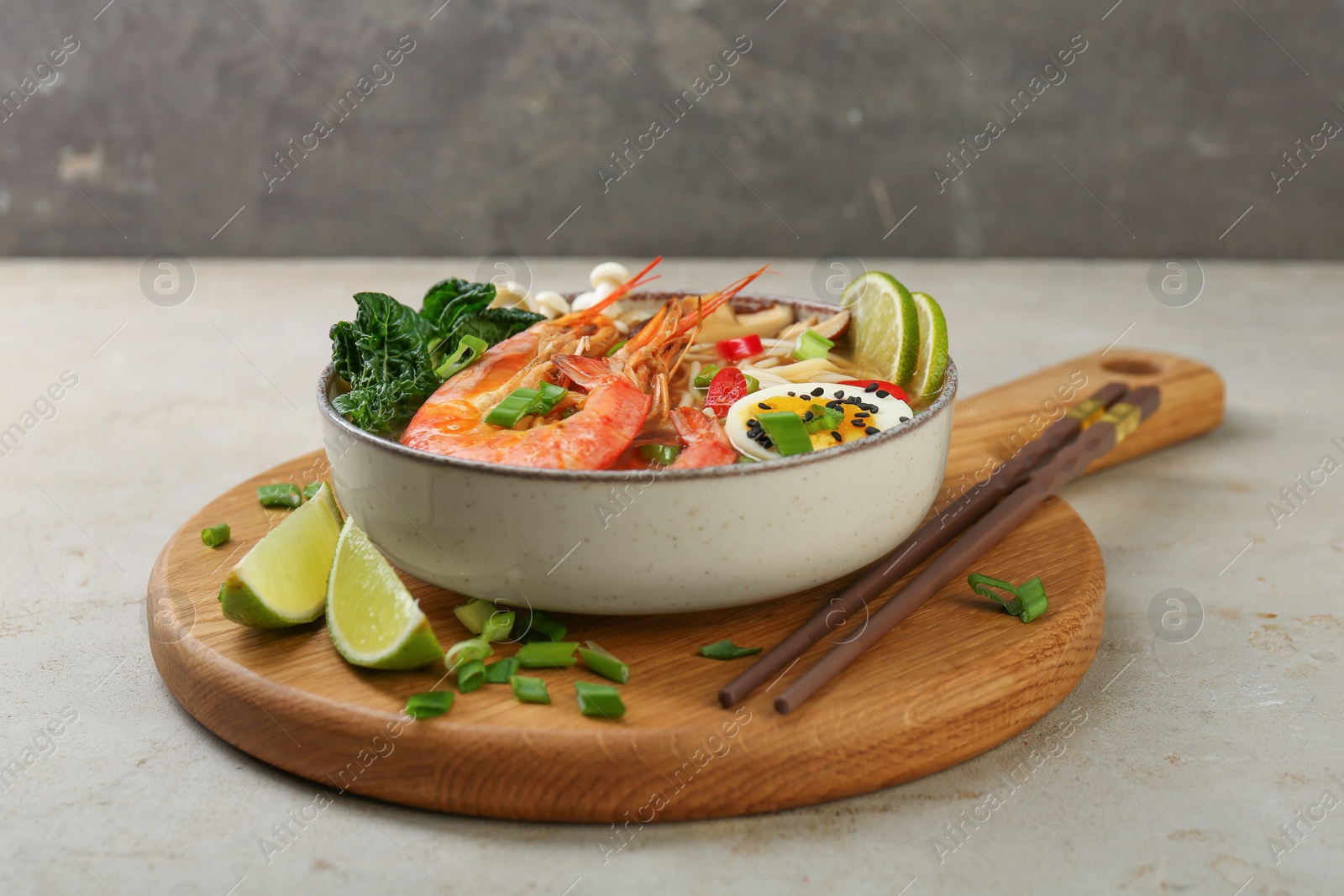 Photo of Delicious ramen with shrimps, egg in bowl and chopsticks on light textured table. Noodle soup