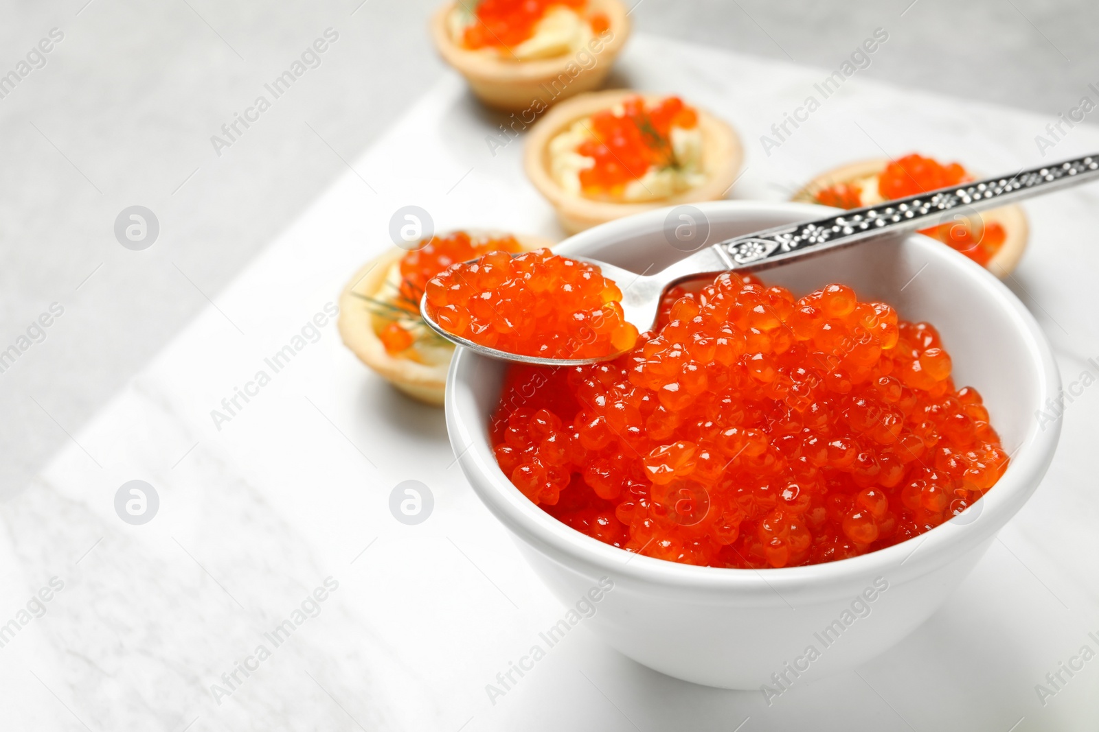 Photo of Spoon and bowl with delicious red caviar on board