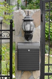 Metal letter box on stone column near fence outdoors
