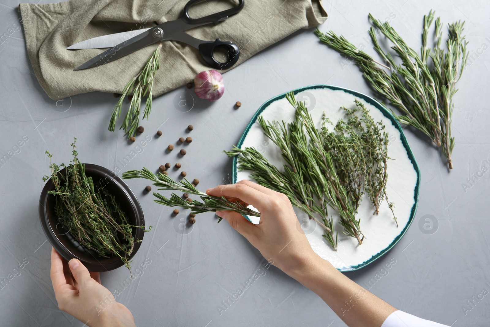 Photo of Woman with rosemary and other aromatic herbs at table, top view