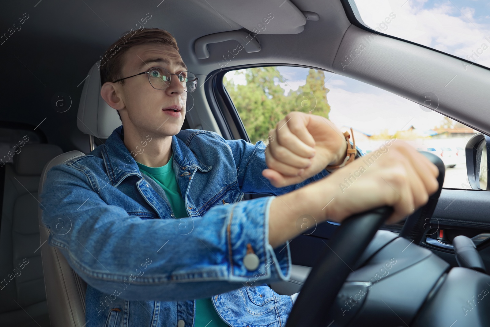 Photo of Emotional young man checking time in car. Being late