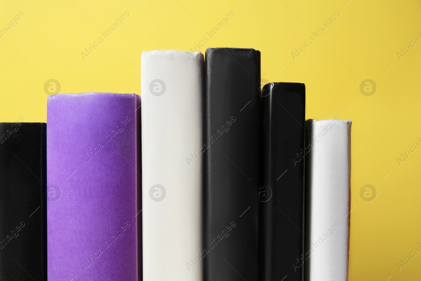 Photo of Collection of hardcover books on yellow background, closeup