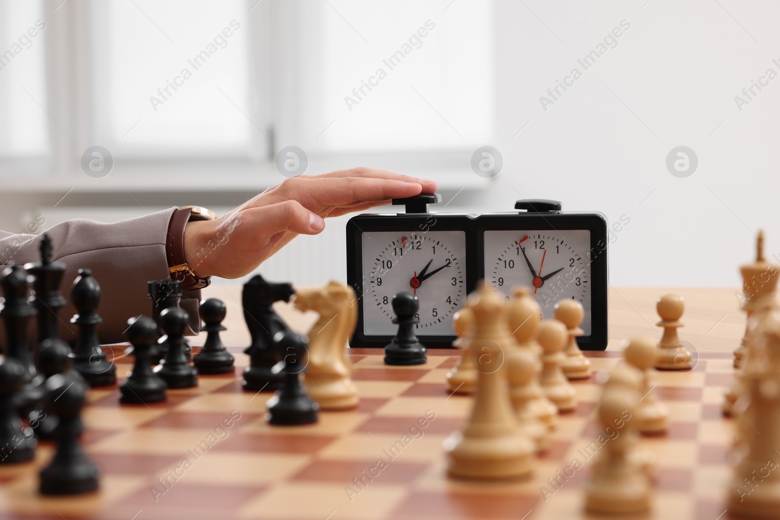 Photo of Man turning on chess clock during tournament at chessboard, closeup