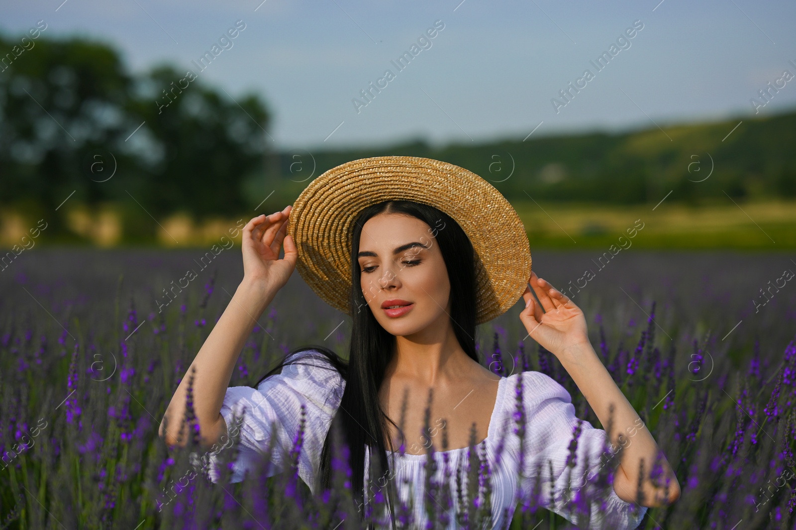 Photo of Beautiful young woman with straw hat in lavender field