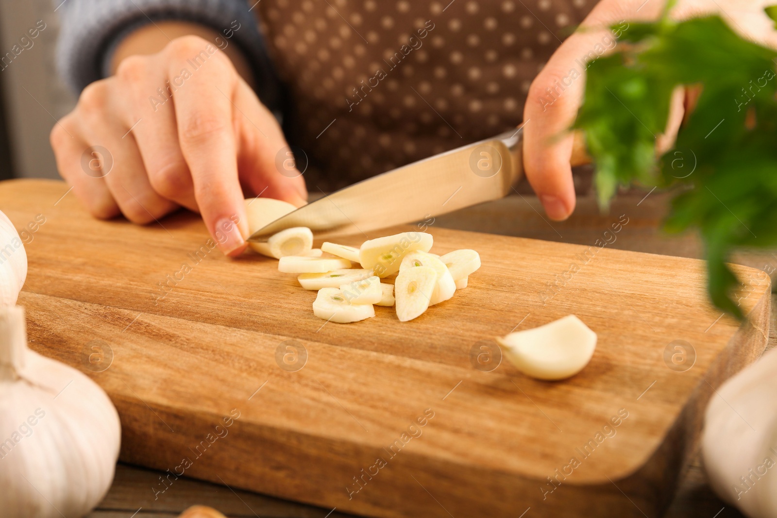 Photo of Woman cutting fresh garlic at table, closeup