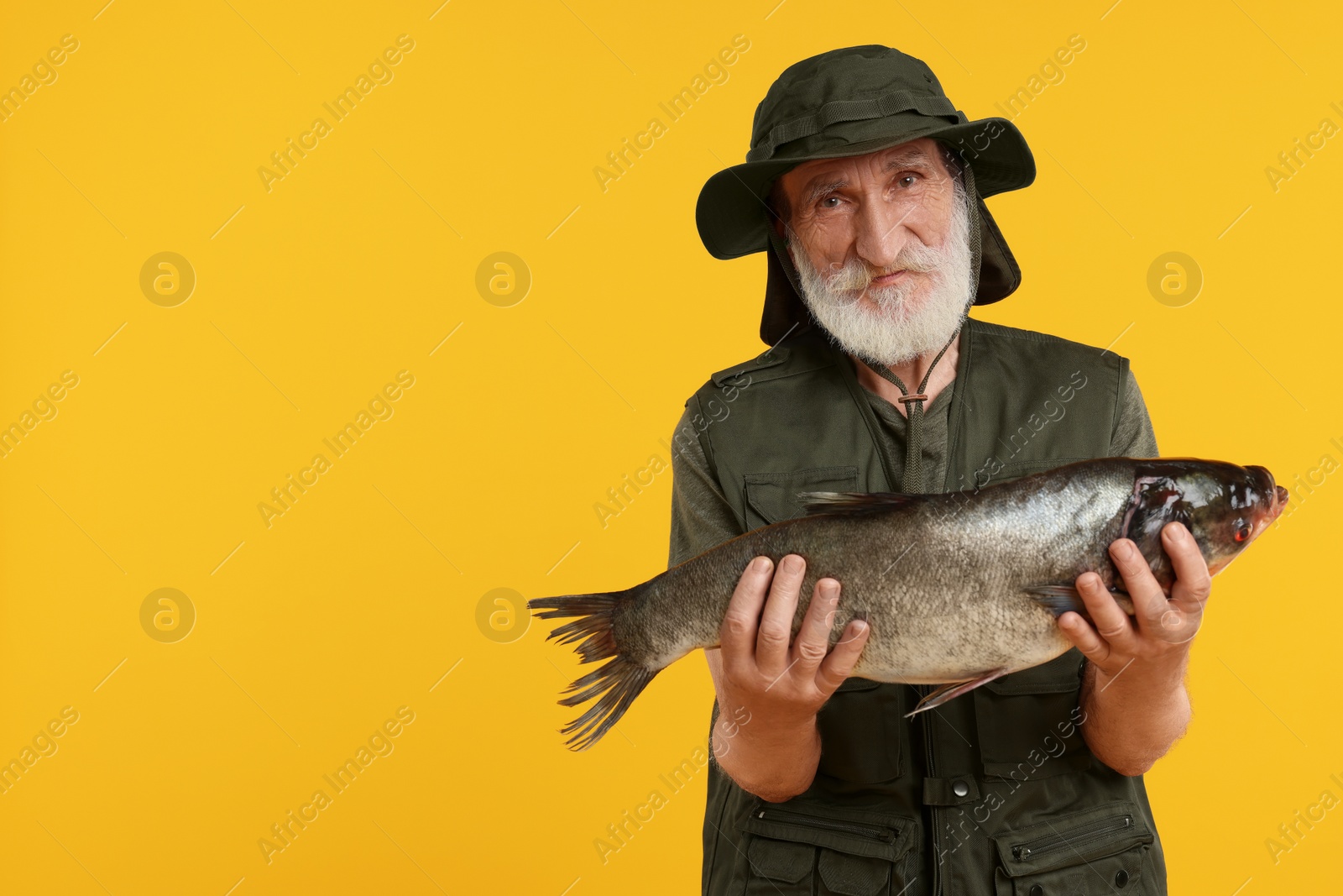 Photo of Fisherman with caught fish on yellow background, space for text