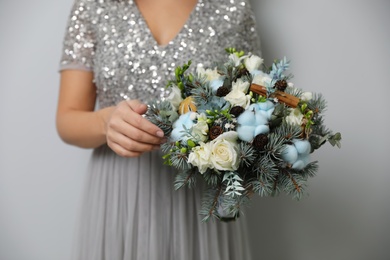 Photo of Bride holding beautiful winter wedding bouquet on light grey background, closeup
