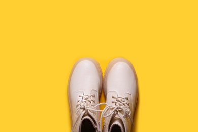 Photo of Pair of stylish leather shoes on yellow background, flat lay. Space for text