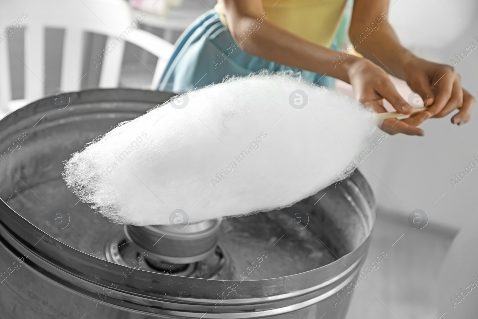 Photo of Woman making cotton candy using modern machine indoors, closeup