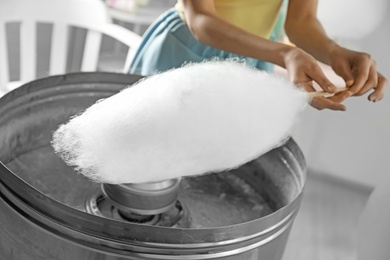 Photo of Woman making cotton candy using modern machine indoors, closeup