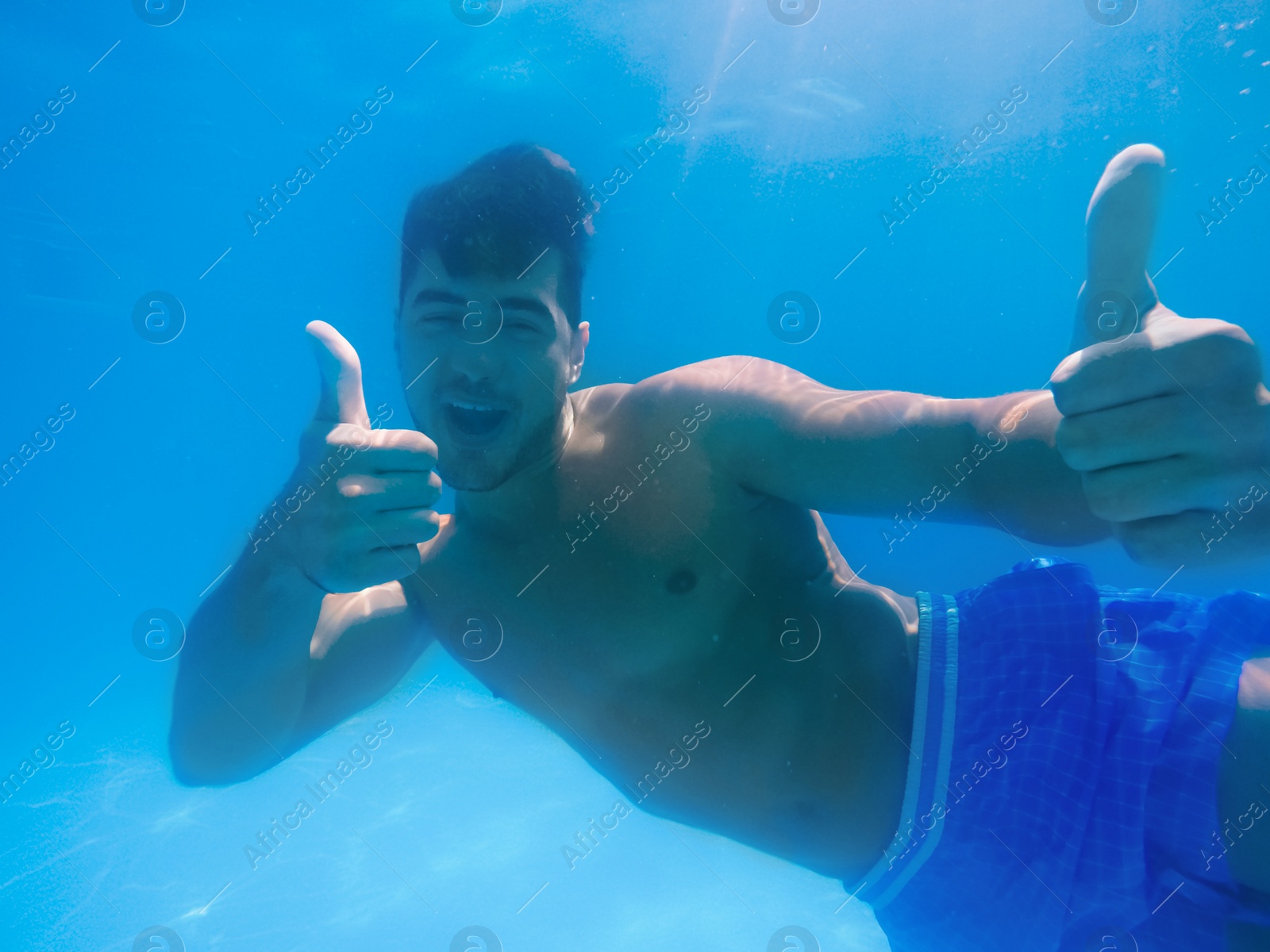 Photo of Handsome young man swimming in pool, underwater view