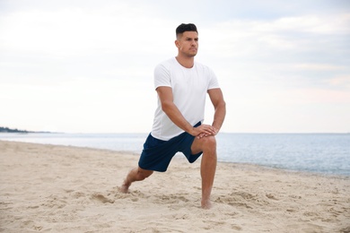 Photo of Muscular man doing exercise on beach. Body training