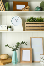 Photo of White shelving unit with photo frames and different decorative elements