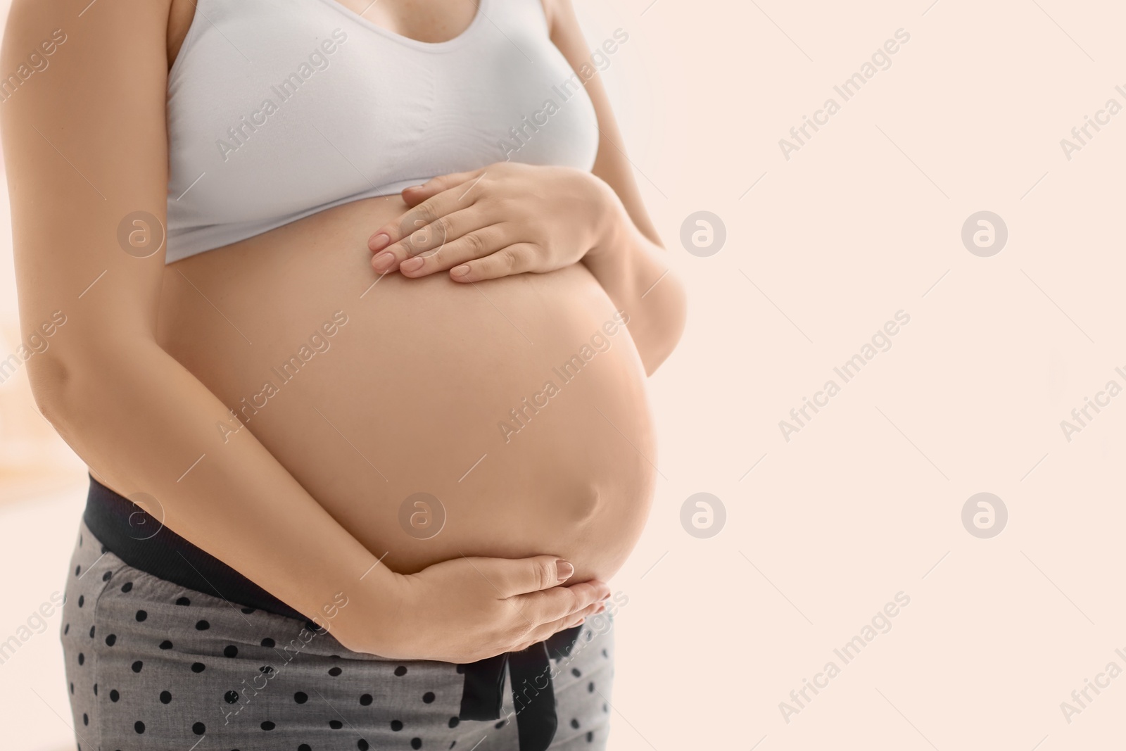 Photo of Pregnant woman after application of body cream on blurred background, closeup